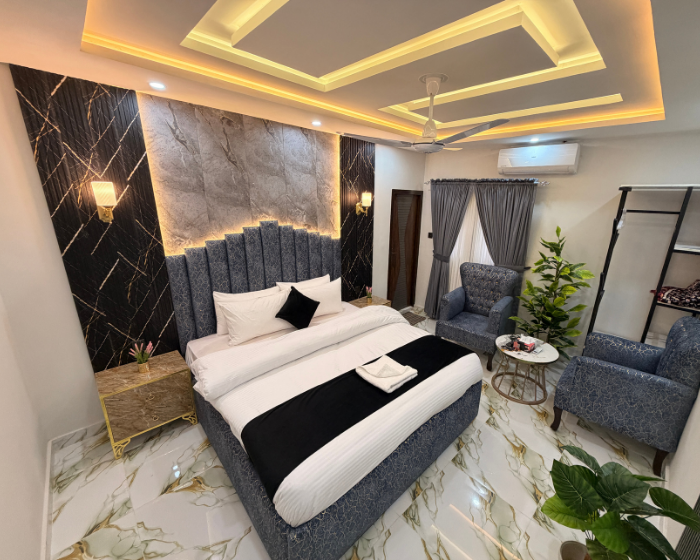 A Hotel Room With A Cozy Bed, A Functional Desk, A Comfortable Chair, A Bright Lamp, And A Stylish Mirror at The Decent Luxury Guest House - 1