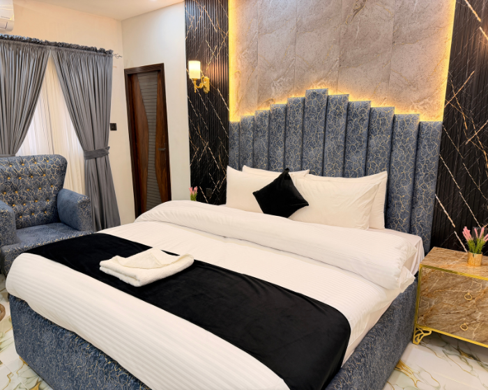 A Hotel Room With A Cozy Bed, A Functional Desk, A Comfortable Chair, A Bright Lamp, And A Stylish Mirror at The Decent Luxury Guest House - 3